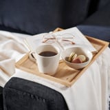 Auf einem dunkelblauen Sofa stehen eine Kaffeetasse und Macarons.