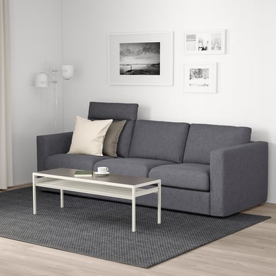 Modernes Wohnzimmer: graues VIMLE-Sofa mit Kissen, weißer Couchtisch, Teppich und Wandkunst.