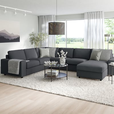 Modernes Wohnzimmer: graues VIMLE L-förmiges Sofa mit Kissen, näher gelegener Beistelltisch, große Fenster, heller Teppich und Kunstwerke.