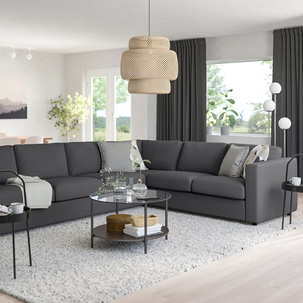 Modernes Wohnzimmer mit dunkelgrauem VIMLE-Sektionsteppich, gesprenkeltem Teppich, schwarzen Vorhängen, Pendelleuchte, dekoriertem Couchtisch und Seitenlampe.