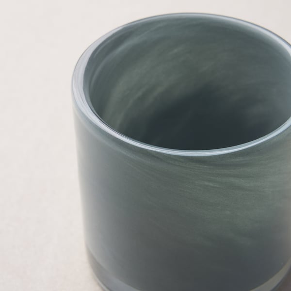 Nahaufnahme eines grünen, handgefertigten Kerzenhalters aus Glas. Glattes, glänzendes Finish und dezentes, elegantes Muster.