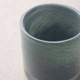 Nahaufnahme eines grünen, handgefertigten Kerzenhalters aus Glas. Glattes, glänzendes Finish und dezentes, elegantes Muster.