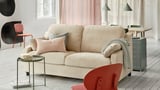 Beigefarbenes Sofa mit rosa Kissen, Glastisch, roter Stuhl, Holzboden