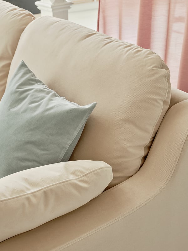 Beiges VINLIDEN-Sofa mit weichen Kissen und hellblauem Kissen.