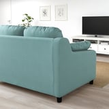 Ein hellblaues VINLIDEN-Sofa in einem Wohnzimmer, geräumig mit hohen Rückenkissen, in der Nähe eines TV-Ständers und eines Teppichs.