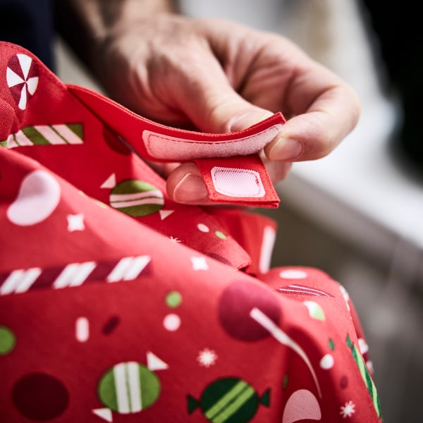 Kind hält festliche Schürze mit Tasche, perfekt für Küchenspaß.
