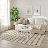 Beige & braun gestreifter VIRKLUND Teppich unter grauem Sofa auf Holzböden.