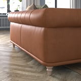 Braune Ledercouch, geschwungene Rückenlehne, Holzbeine, gemütliches Design.