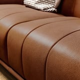 Nahaufnahme des braunen Ledersofas VISKAFORS mit geschwungenen Linien und glatter Textur.