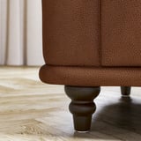 Nahaufnahme des braunen Ledersofas VISKAFORS mit strukturierter Polsterung und Holzbein mit rundem Design.