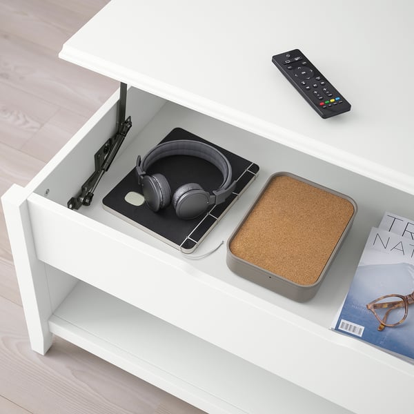 Weißer VITTERYD-Couchtisch mit verstellbarer Platte, Kopfhörern, Fernbedienung und Zeitschrift auf der unteren Ablage.