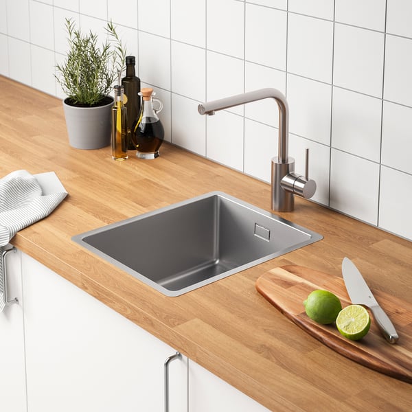 Moderne Küchenspüle mit Wasserhahn, Messern, Limetten und Flaschen.