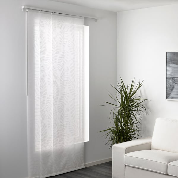 Durchsichtige Vorhänge, die ein Fenster abdecken, lassen Licht herein und bieten gleichzeitig Privatsphäre, mit einer modernen Pflanze und einem Stuhl in der Nähe.