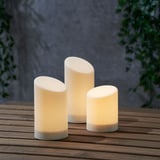 Three led candles of varying heights on a wooden surface, designed for outdoor use, with built-in timers for automated lighting.