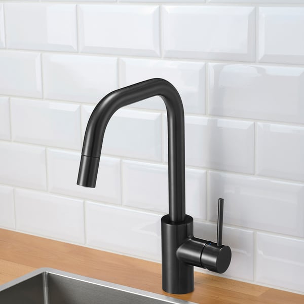 Black kitchen faucet with pull-out spout, set against white brick backsplash, wooden counter, and metal sink.
