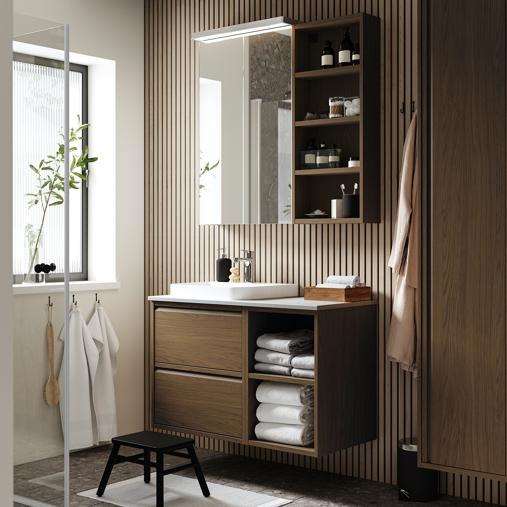 Modern bathroom with wooden cabinet & marble basin, featuring open & closed storage, towels, and plants.