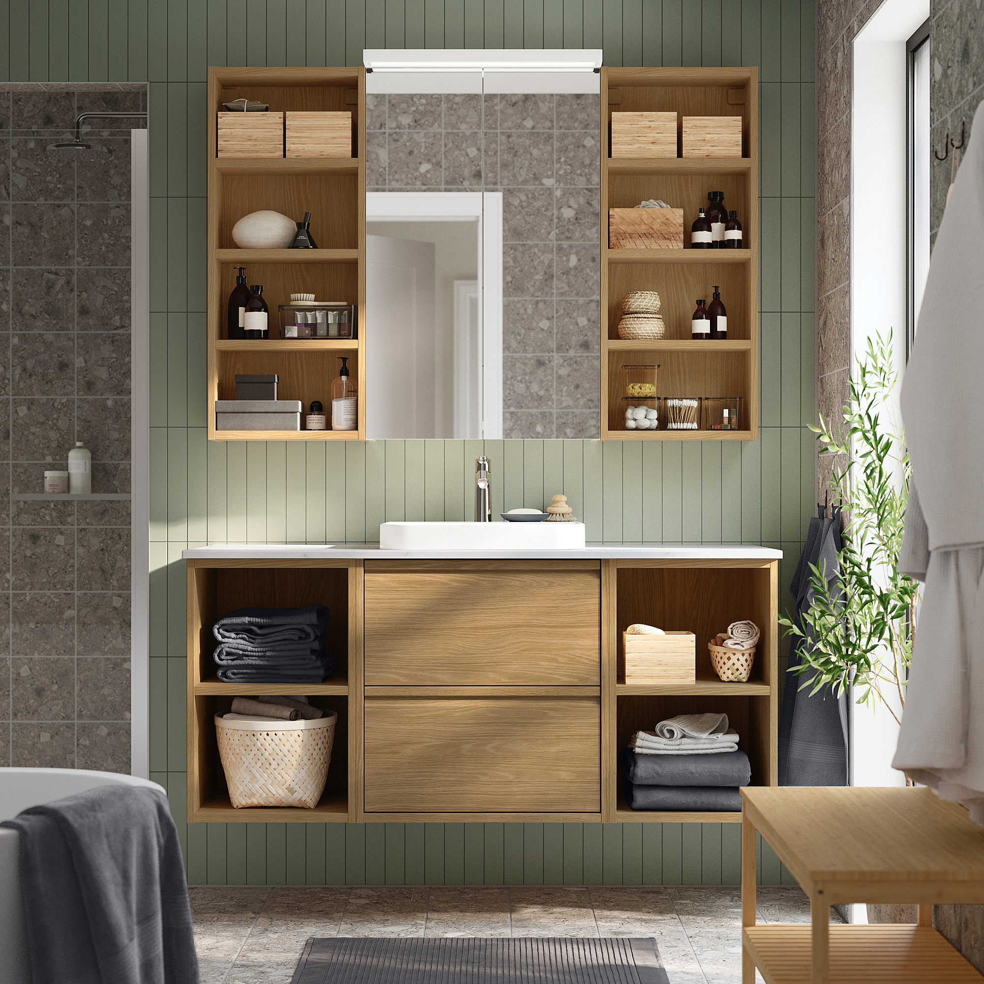 Modern green & wooden bathroom with storage, sink, mirror, & plant.