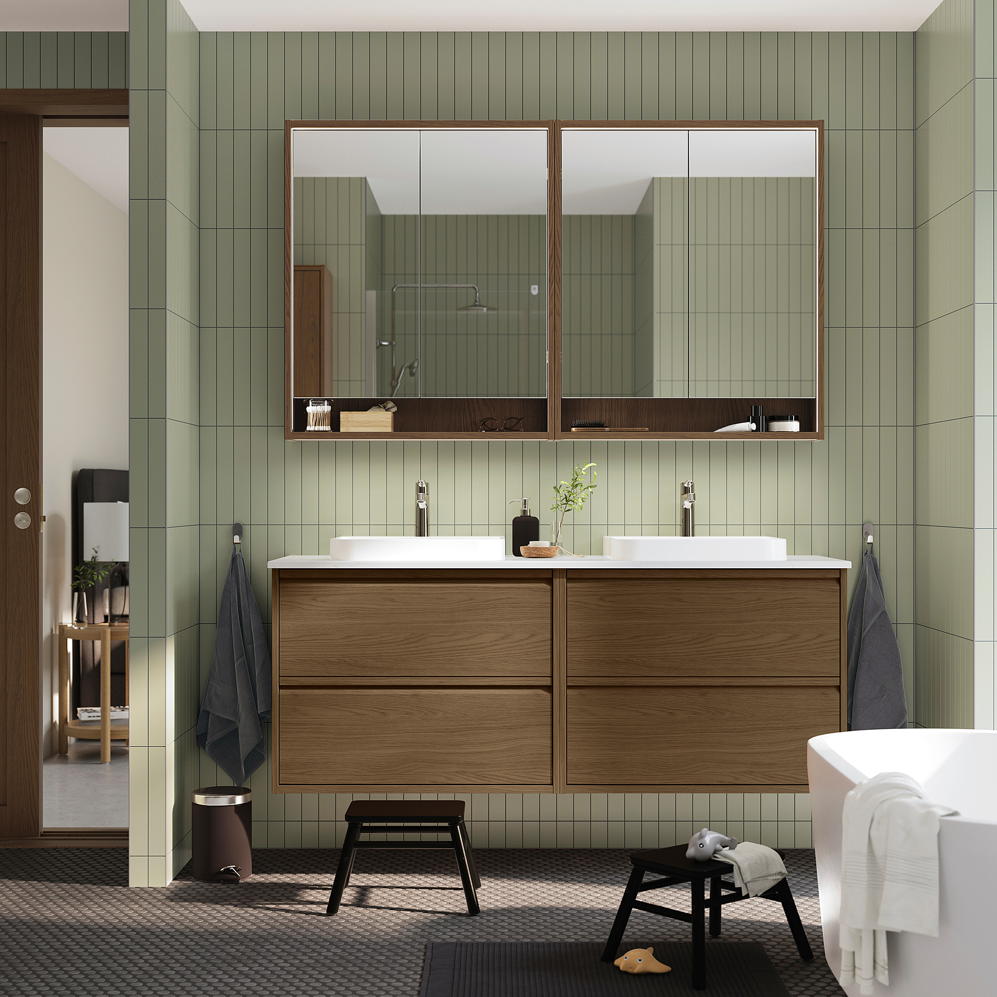 Modern bathroom with brown oak ÄNGSJÖN vanity, dual chrome sinks, green tiles, large mirror, and storage.