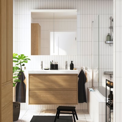 Modern bathroom with ÄNGSJÖN light oak vanity, double white basin, black accents, and large mirror.
