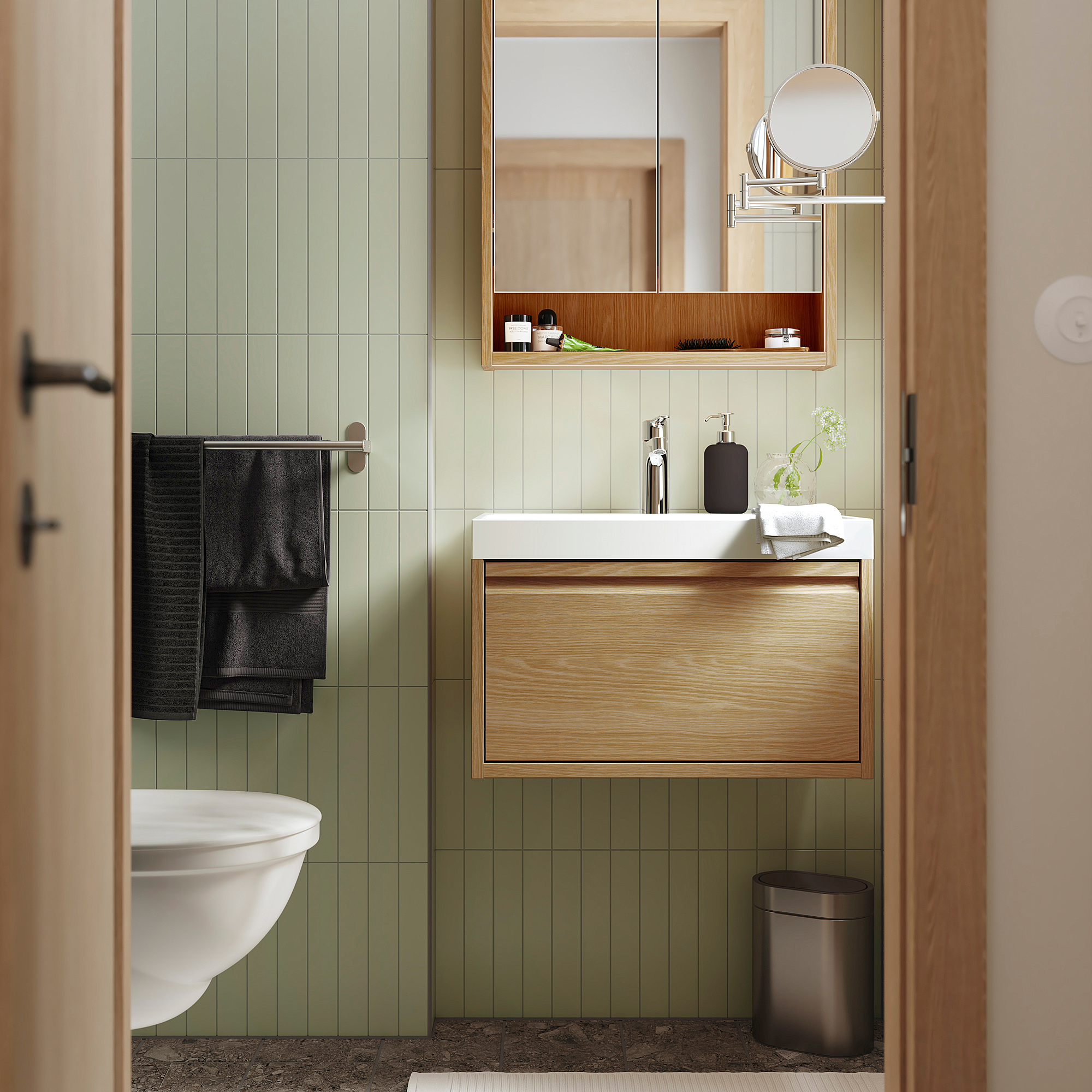 Stylish bathroom with green tiles, wooden accents, sink, mirror, and black towel.