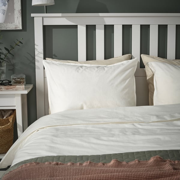 ÄNGSLILJA pillowcases, light beige, soft cotton, rectangular, on bed, with headboard. Neutrally styled, cozy bedroom.