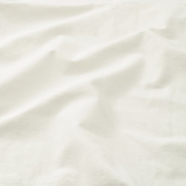 Soft, white, textured pillowcase fabric. Light folds and creases suggest high-quality, breathable cotton.