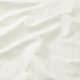 Soft, white, textured pillowcase fabric. Light folds and creases suggest high-quality, breathable cotton.
