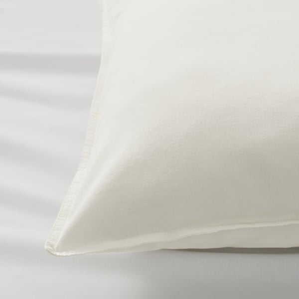 Close-up of white pillowcase, soft fabric, neat stitching, on white surface.