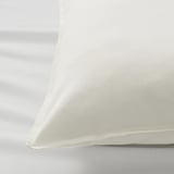 Close-up of white pillowcase, soft fabric, neat stitching, on white surface.