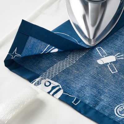 Blue glow-in-dark curtains with space-themed white patterns. Made from recycled polyester and cotton fabric, featuring tab headings and tie-backs.