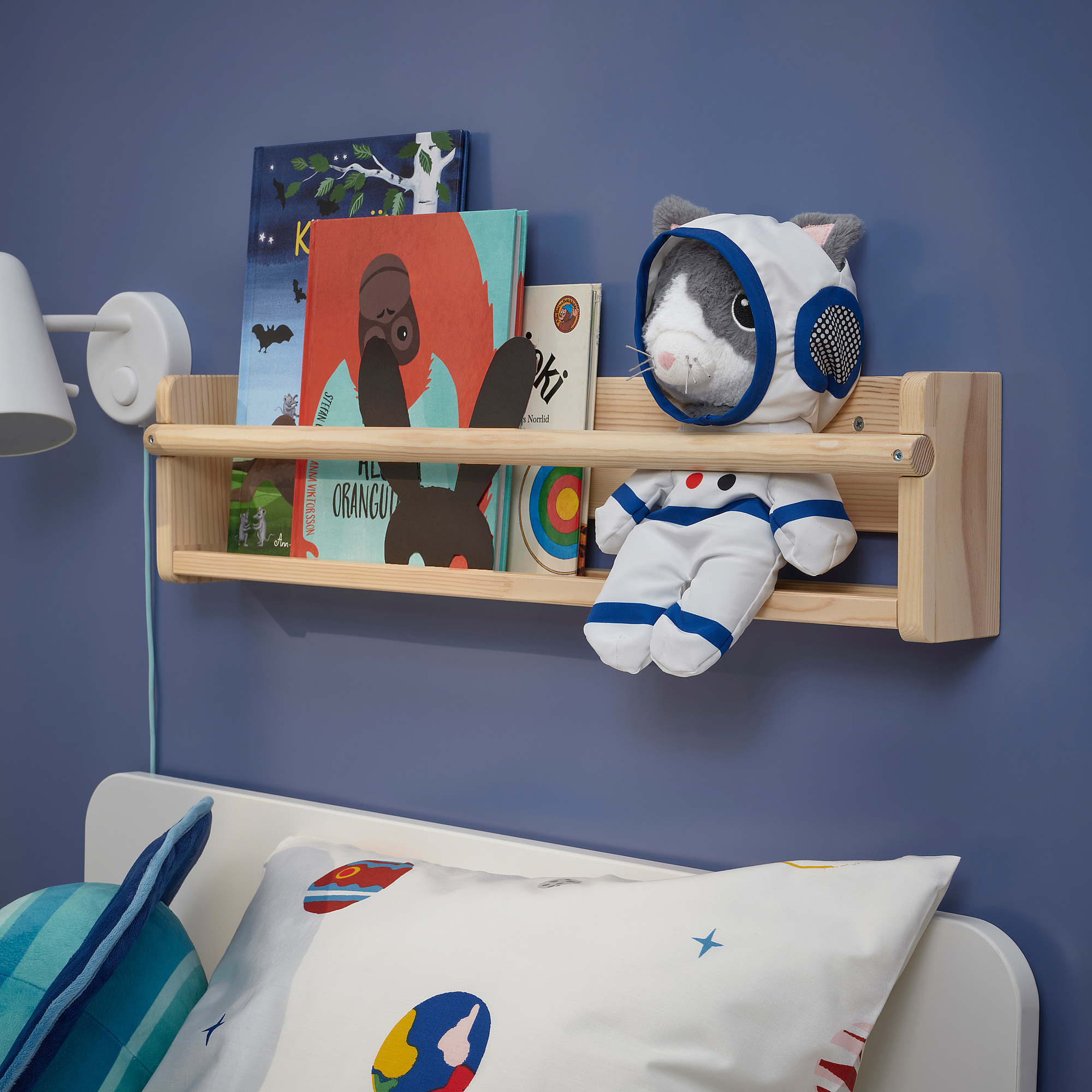 Blue kids room with astronaut cat toy on wooden shelf near bed.
