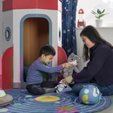 A child plays with a woman, both holding a plush grey cat in a colorful, space-themed room.