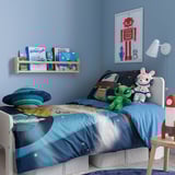 Kids blue-themed bedroom with space decor, bed, bookshelf, and plush toys.