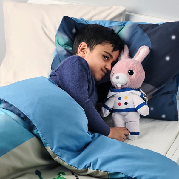 Boy in bed hugs astronaut sheep, perfect for play and sleep.