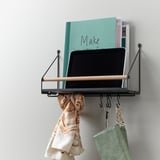 Wall-mounted organizer with shelf, holding laptop, books, and handbag, plus hooks for accessories.