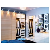 Bedroom with wooden wardrobe, white dresser, mirror, and blue walls. Picture frames and vase on dresser.