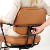 Person adjusting office chairs armrest. Brown leather chair with black metal base.