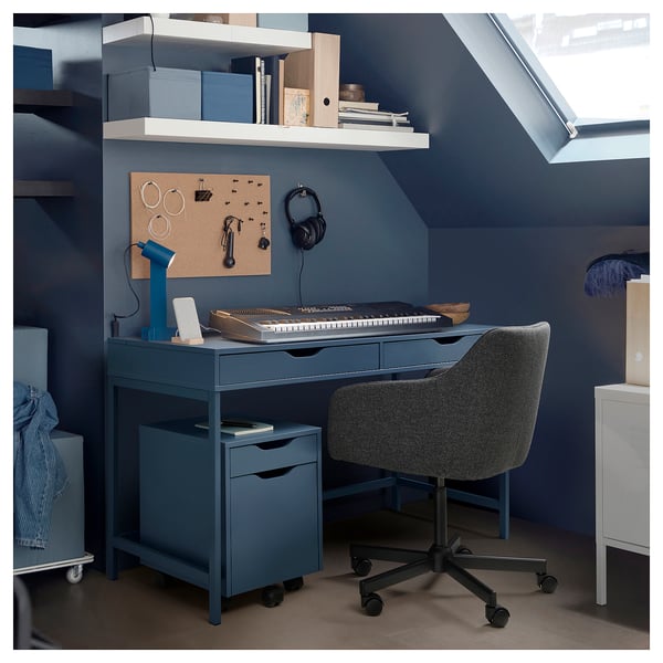 Modern home office with blue ALEX desk, keyboard tray, corkboard, and grey chair.