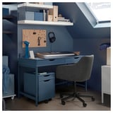 Modern home office with blue ALEX desk, keyboard tray, corkboard, and grey chair.