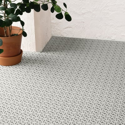 A tiled outdoor floor with triangular patterns, ideal for balconies. A potted plant sits on the left, highlighting its weather-resistant design.