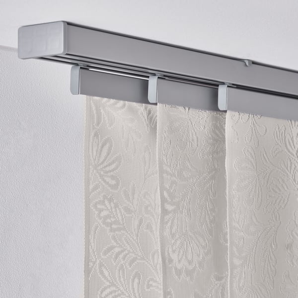 Curtain panel with leaf pattern, hangs from metallic rail, filters light.