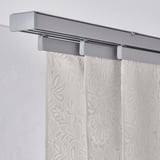Curtain panel with leaf pattern, hangs from metallic rail, filters light.