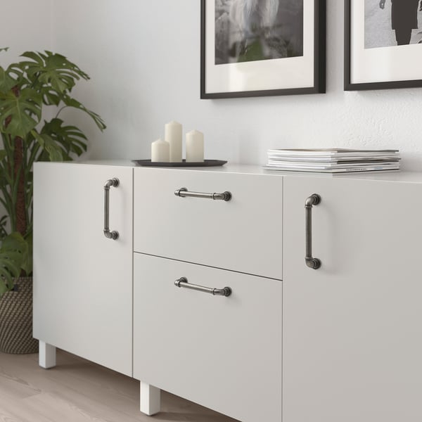 Modern, white cabinet with ANDERSFORS silver handles, black and white decor, plant on left, small on white floor.