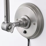 Silver adjustable wall lamp with a brushed finish and flexible arm, mounted on a round base. The switch is located on the side of the base.