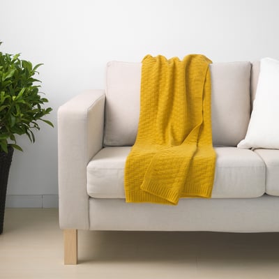 Bright yellow throw blanket draped casually over a cozy white sofa.
