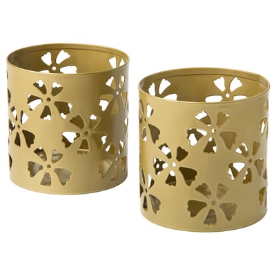 Two gold-colored cylindrical tealight holders with floral cut-out patterns, made of coated galvanized steel.