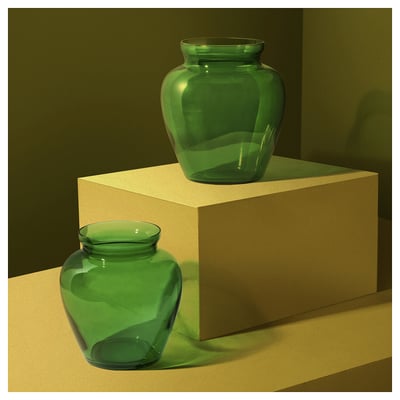 Green glass vases, one large, one small, mouth-blown, organic shape, displayed on pedestals.