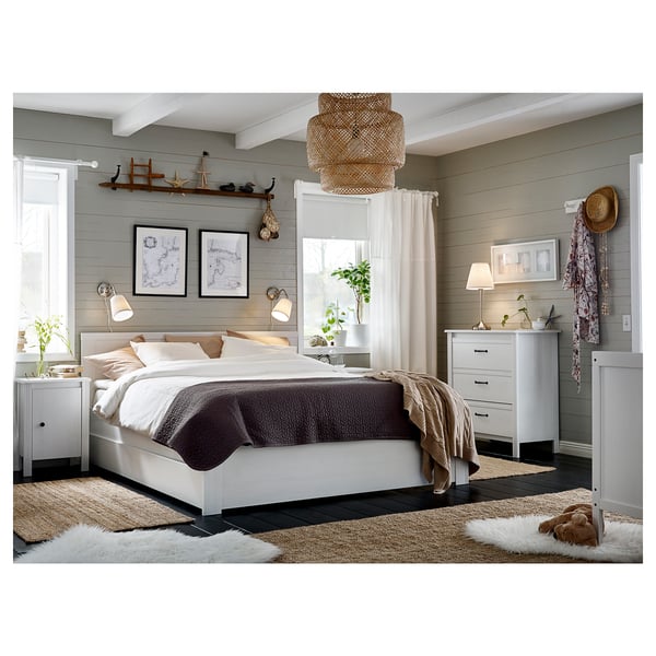 Cozy bedroom with white bedding, brown blanket, two nightstands with lamps, antique decor.