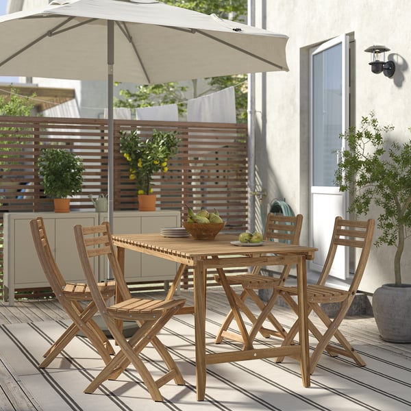 Wooden ASKHOLMEN patio set with table, 4 chairs, and cushions on deck, shaded by large umbrella.