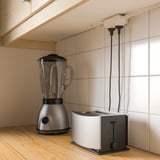 Modern kitchen with blender, toaster, and power strips.
